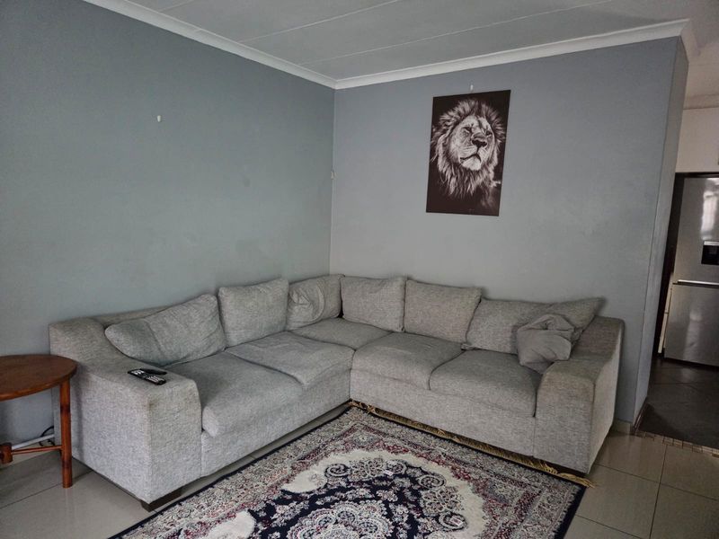 A living room area featuring neutral grey walls, tiled flooring, and coved ceiling detailing.