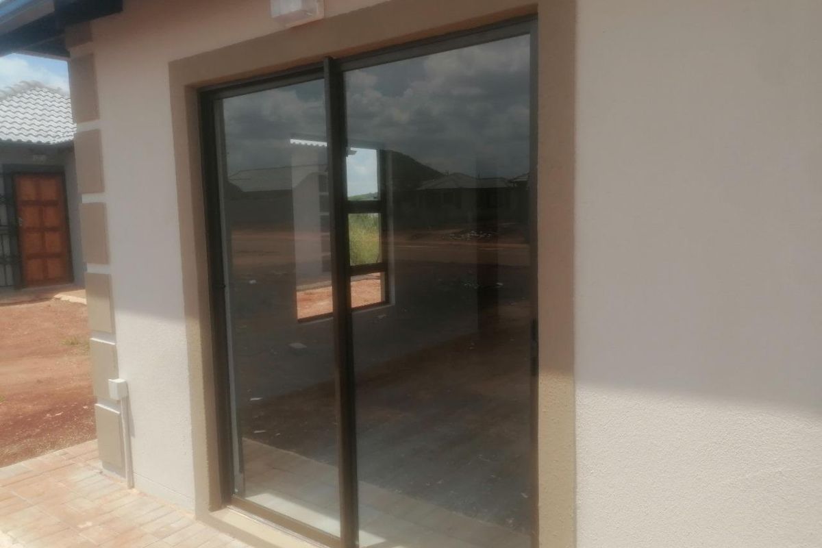 Exterior view of a modern sliding glass door entrance with a paved patio area and neutral exterior wall finish.