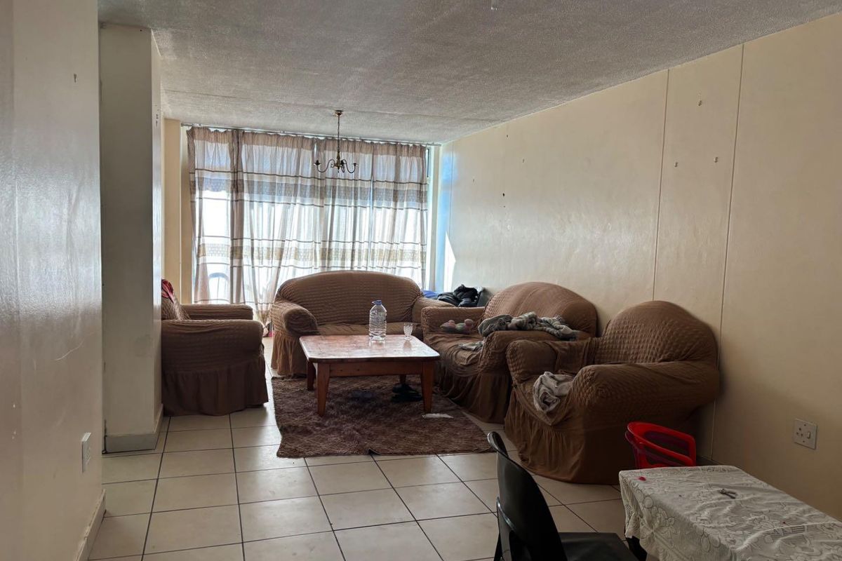 A living room featuring tiled flooring and a large sliding glass door, requiring cosmetic updates to the walls and ceiling to improve its overall condition.