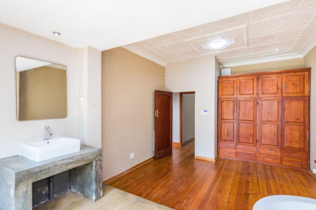 Bedroom featuring hardwood flooring, a decorative pressed metal ceiling, built-in wooden wardrobe, and a modern concrete vanity with a vessel sink.