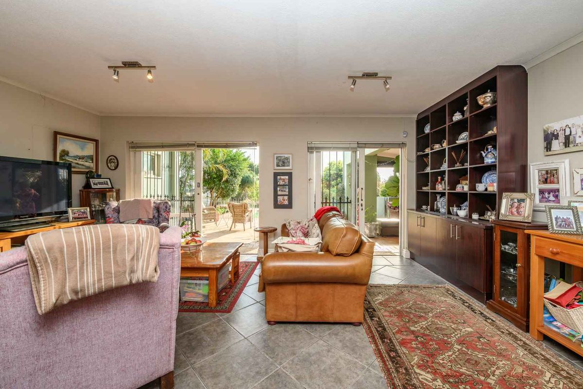 Spacious living room featuring large sliding glass doors leading to an outdoor patio, complemented by built-in dark wood shelving and tiled flooring.