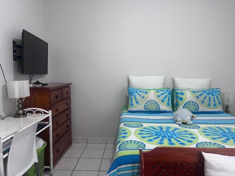 A functional bedroom featuring tiled flooring and a wall-mounted television bracket, offering a clean and simple living space.