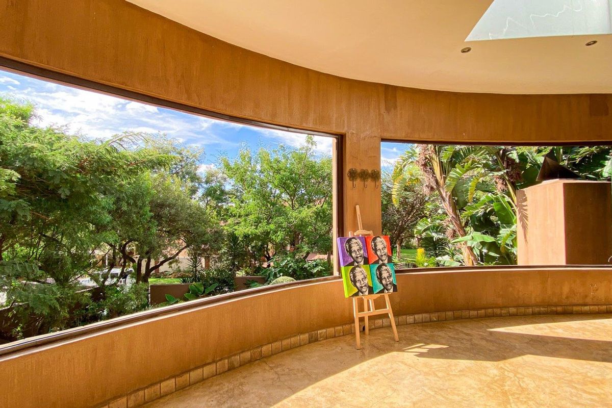 A bright, curved living area featuring expansive floor-to-ceiling windows that offer panoramic views of the surrounding lush garden and greenery.