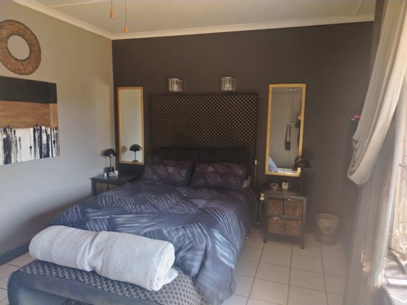 A bedroom featuring tiled flooring and wall-mounted accent lighting.