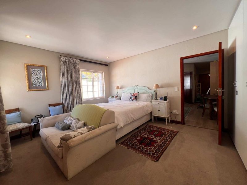 A spacious bedroom featuring neutral wall finishes, recessed downlighting, and a built-in wardrobe, offering a comfortable and functional living space.