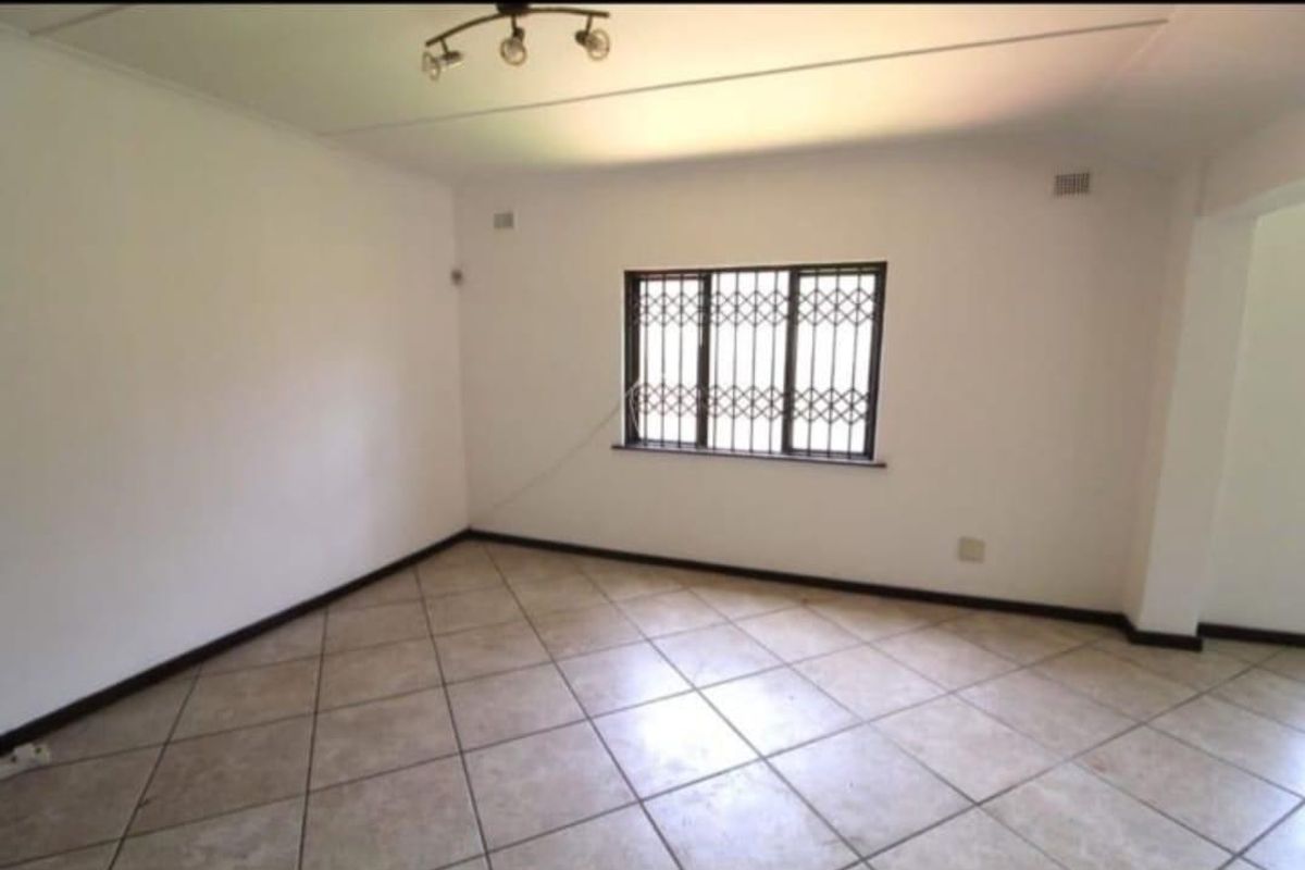 A bright, empty living room featuring neutral ceramic floor tiles and security bars on the window, providing a clean canvas for personalization.