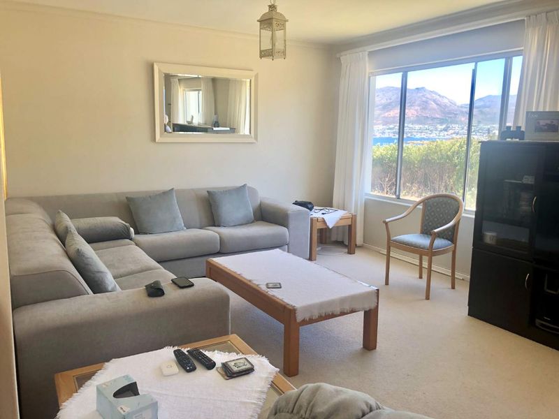 A comfortable living room featuring large windows that provide natural light and scenic mountain and water views.