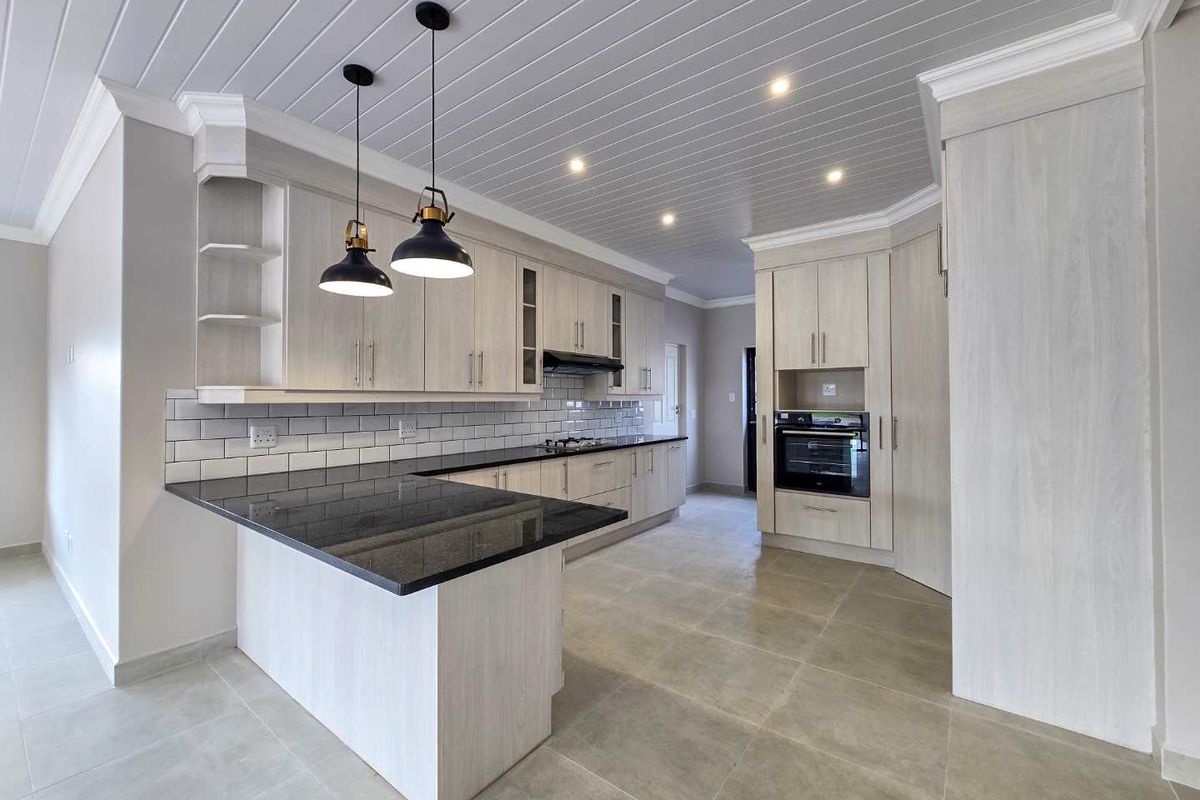 Modern kitchen featuring light wood cabinetry, granite countertops, subway tile backsplash, built-in oven, hob, and stylish pendant lighting with a tongue and groove ceiling.