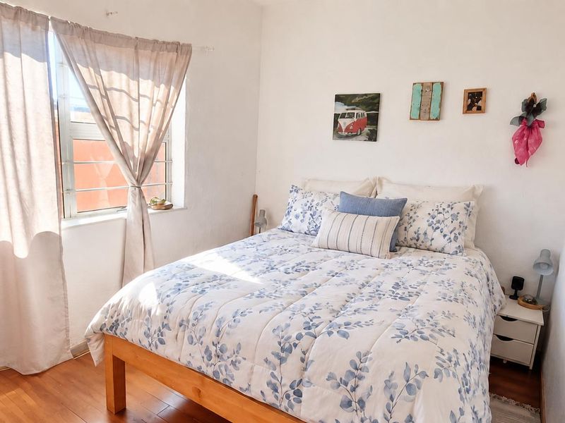A bright bedroom featuring laminate flooring and a window with natural light.