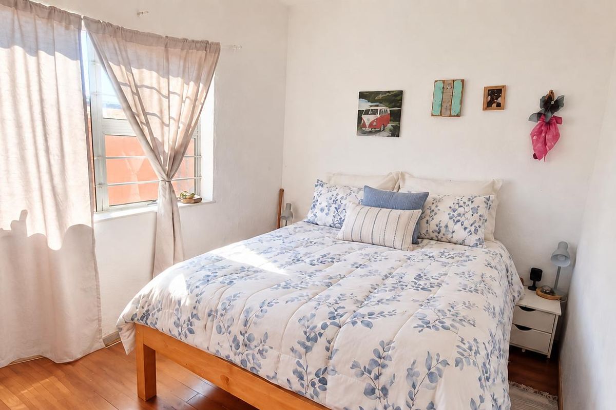 A bright bedroom featuring laminate flooring and a window with natural light.