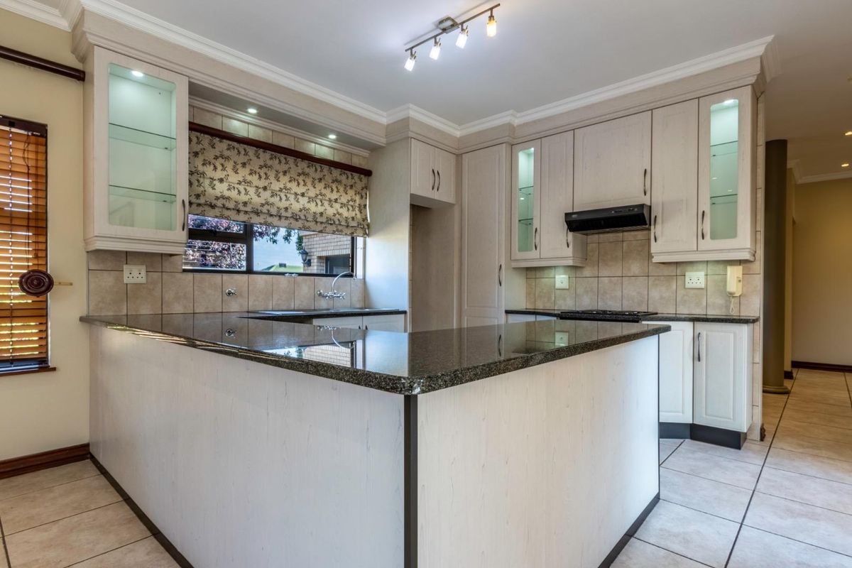 A well-maintained kitchen featuring granite countertops, light-toned cabinetry, integrated lighting, and tiled flooring, offering a functional and clean workspace.