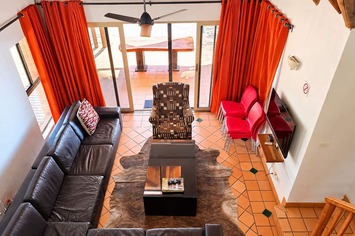 A living room featuring terracotta floor tiles, a ceiling fan, and large sliding glass doors that provide access to an outdoor patio area.