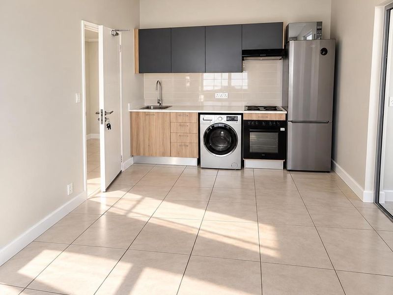 Modern compact kitchen featuring light wood-finish lower cabinets, dark upper cabinetry, tiled backsplash, and integrated appliances including an oven and hob.