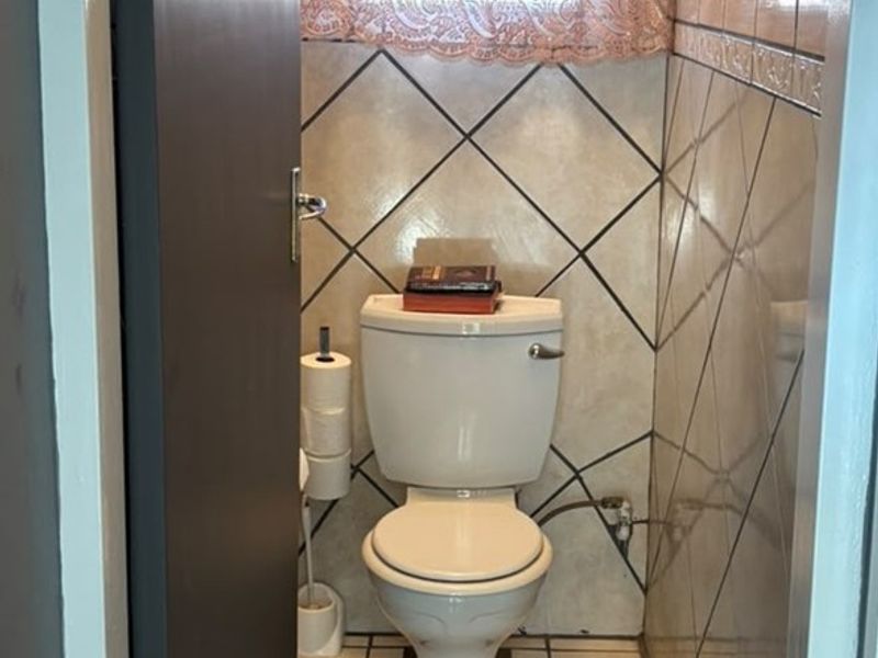 A compact bathroom featuring ceramic wall and floor tiling with a standard white toilet suite.