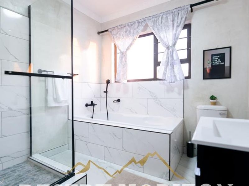Modern bathroom featuring a glass-enclosed shower, built-in bathtub, and elegant marble-look tiling with contemporary black matte fixtures.