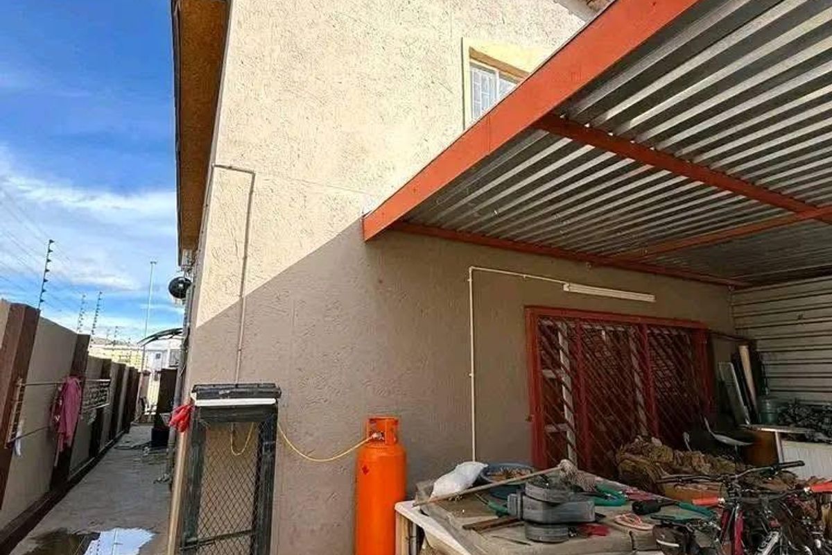 Side exterior area featuring a covered patio structure, paved flooring, and access to the side of the house.