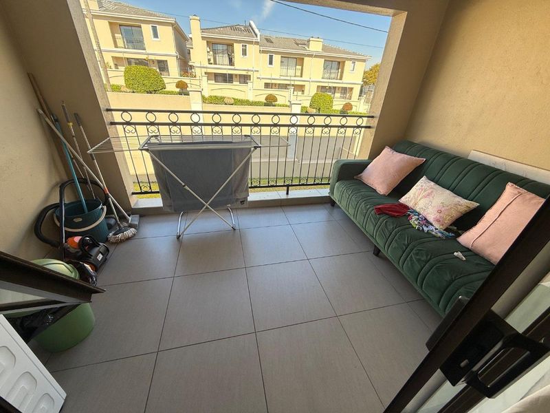 A covered balcony featuring tiled flooring and a decorative wrought iron balustrade, offering an outdoor space for relaxation.