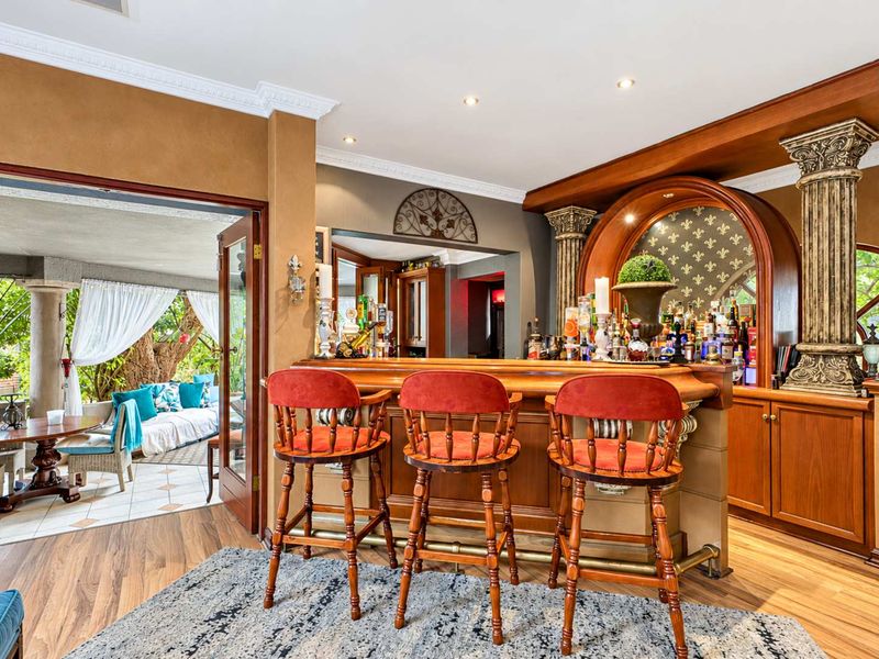 A well-appointed home bar featuring custom cabinetry, decorative columns, and direct access to an outdoor patio area.