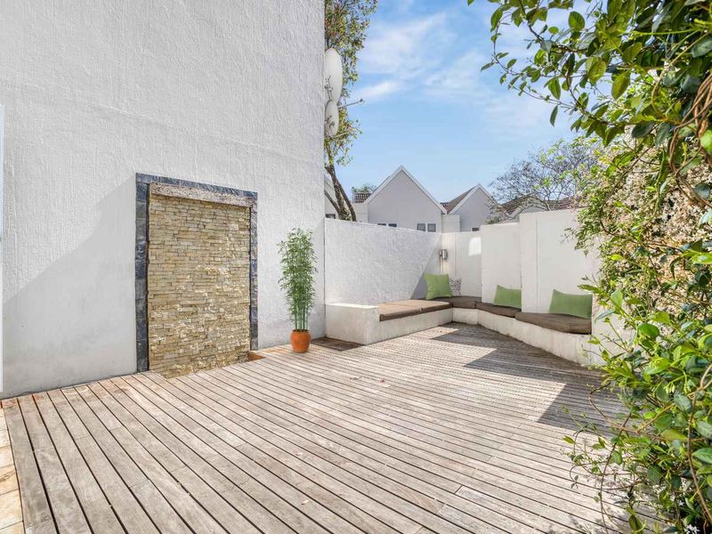 A private outdoor patio featuring timber decking, a stone feature wall, and built-in bench seating, perfect for relaxed outdoor living.