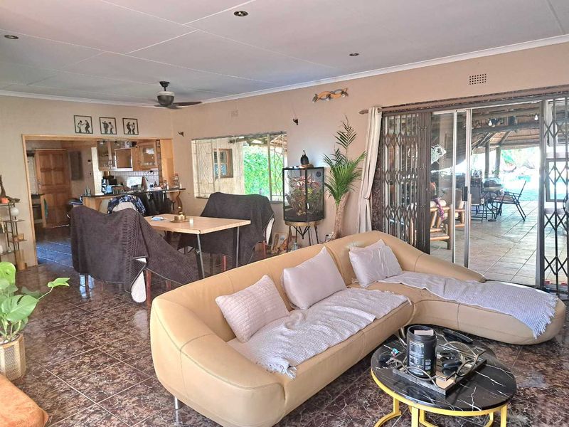 Spacious open-plan living area featuring tiled floors, recessed lighting, and direct access to an outdoor patio through large sliding glass doors.