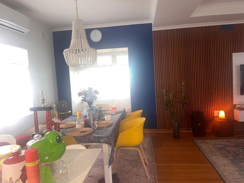 Dining area featuring hardwood flooring, a decorative timber slat feature wall, and a split system air conditioner.