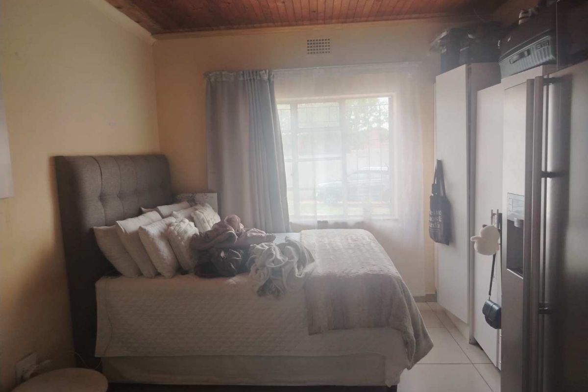 A bedroom featuring a timber ceiling, tiled flooring, and built-in cupboards, providing a functional space with natural light.