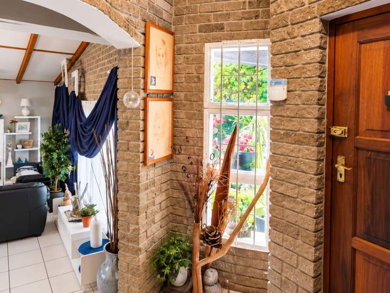 Entrance foyer featuring exposed brick walls, tiled flooring, and a solid timber front door, leading into an open-plan living area.