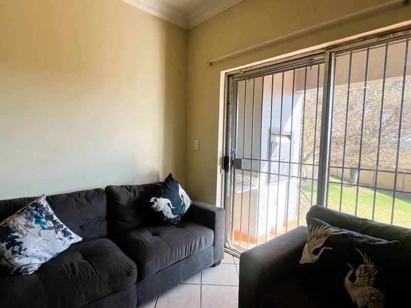 A living room featuring tiled flooring and a sliding glass door with an integrated security gate, providing access to the outdoor area.