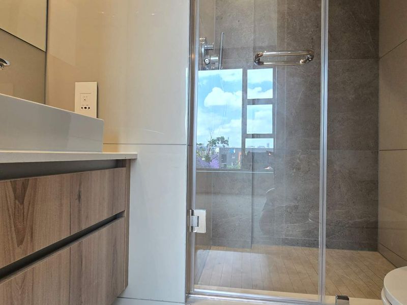Modern bathroom featuring a floating vanity with vessel sink, glass-enclosed shower, and contemporary large-format tiling throughout.