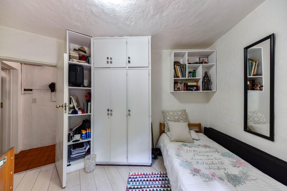 A bedroom featuring built-in white cabinetry, integrated shelving, and light-toned laminate flooring.