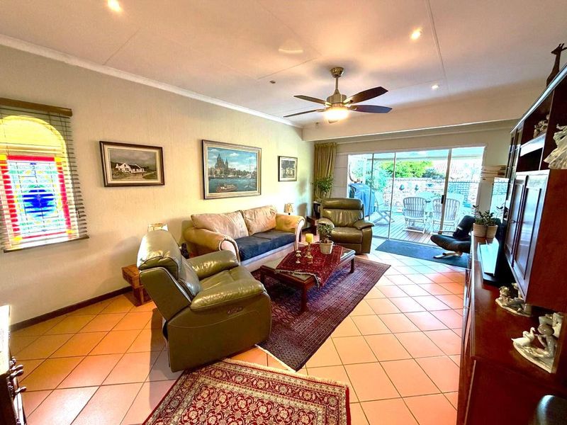 Spacious living room featuring tiled flooring, a ceiling fan, and large sliding glass doors providing direct access to the outdoor patio area.