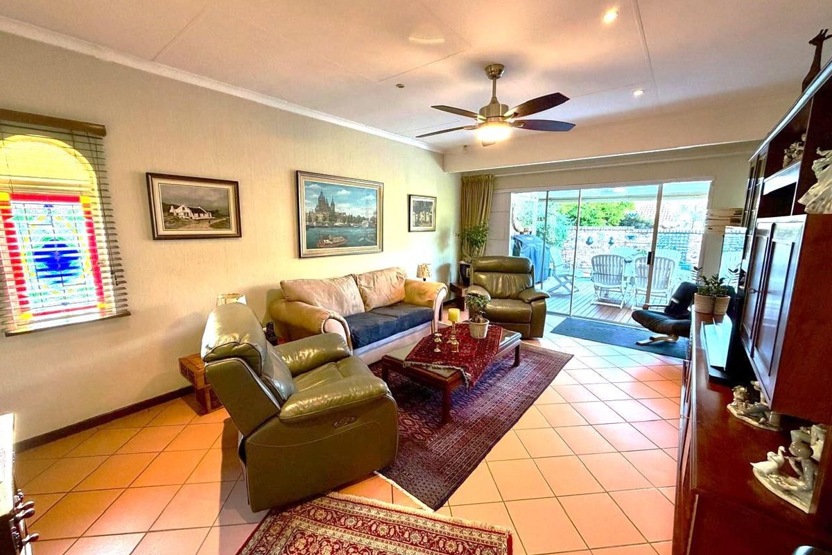 Spacious living room featuring tiled flooring, a ceiling fan, and large sliding glass doors providing direct access to the outdoor patio area.