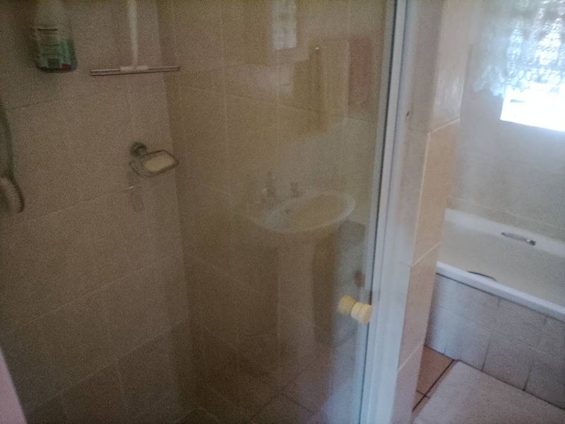 A dated bathroom featuring a shower enclosure, pedestal basin, and bathtub with tiled finishes throughout.