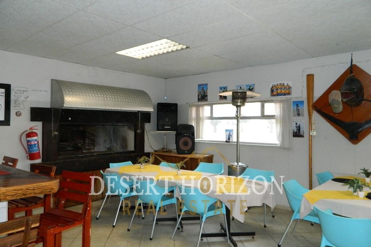 A functional indoor entertainment area featuring a built-in braai with a metal extractor hood, tiled flooring, and drop ceiling panels.