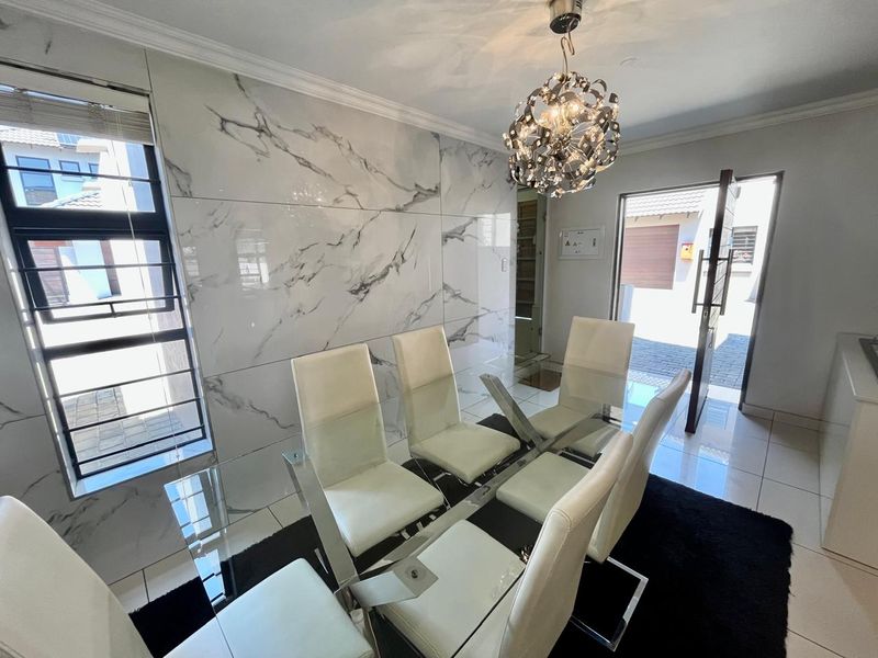 Modern dining area featuring large-format marble-look wall tiles, polished ceramic flooring, and a contemporary statement pendant light fixture.