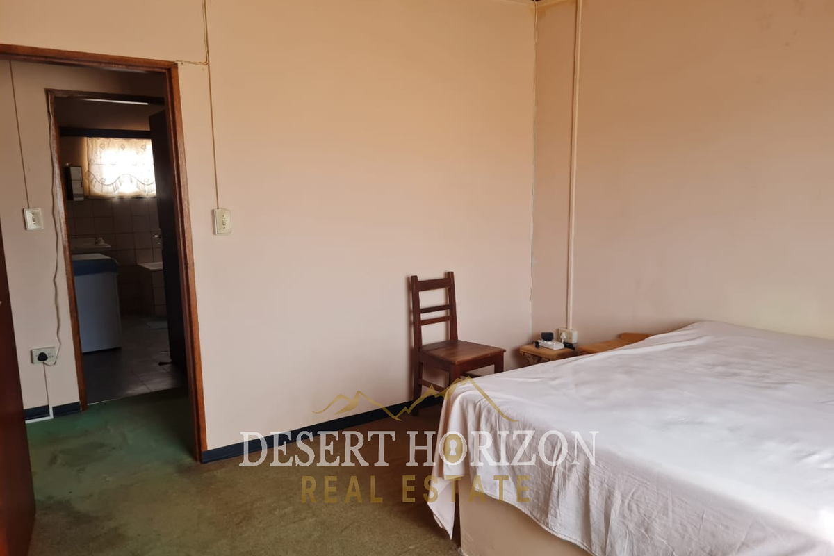 A bedroom featuring carpet flooring and a doorway leading to an adjacent utility area, requiring cosmetic updates to improve its overall condition.
