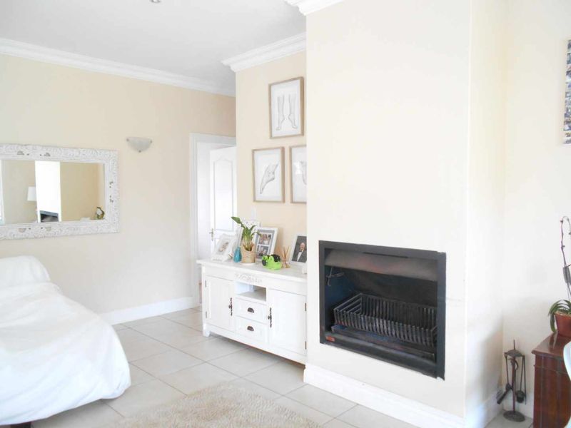 A bright living room featuring a built-in fireplace, tiled flooring, and classic crown molding, offering a neutral and comfortable living space.