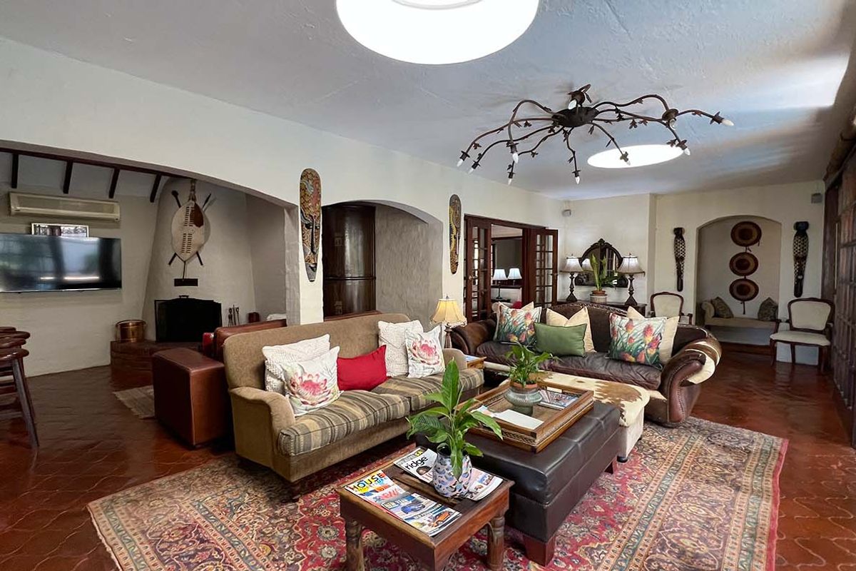Spacious living room featuring terracotta tiled flooring, a built-in fireplace, arched architectural details, and decorative ceiling lighting.