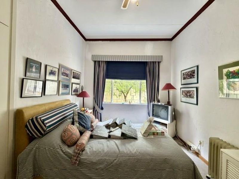 A standard bedroom featuring a window with a pelmet, built-in wardrobe, and neutral wall finishes.