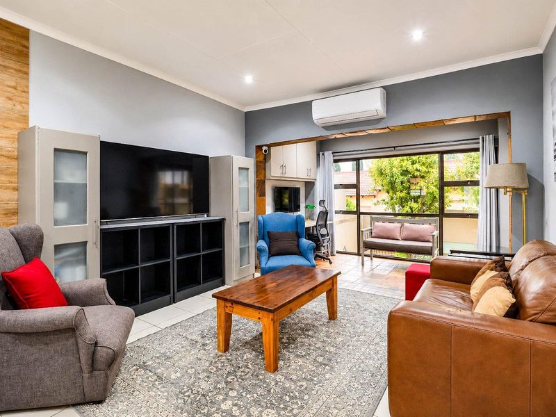 A well-maintained living room featuring tiled flooring, recessed lighting, an air conditioning unit, and large sliding glass doors leading to an outdoor area.