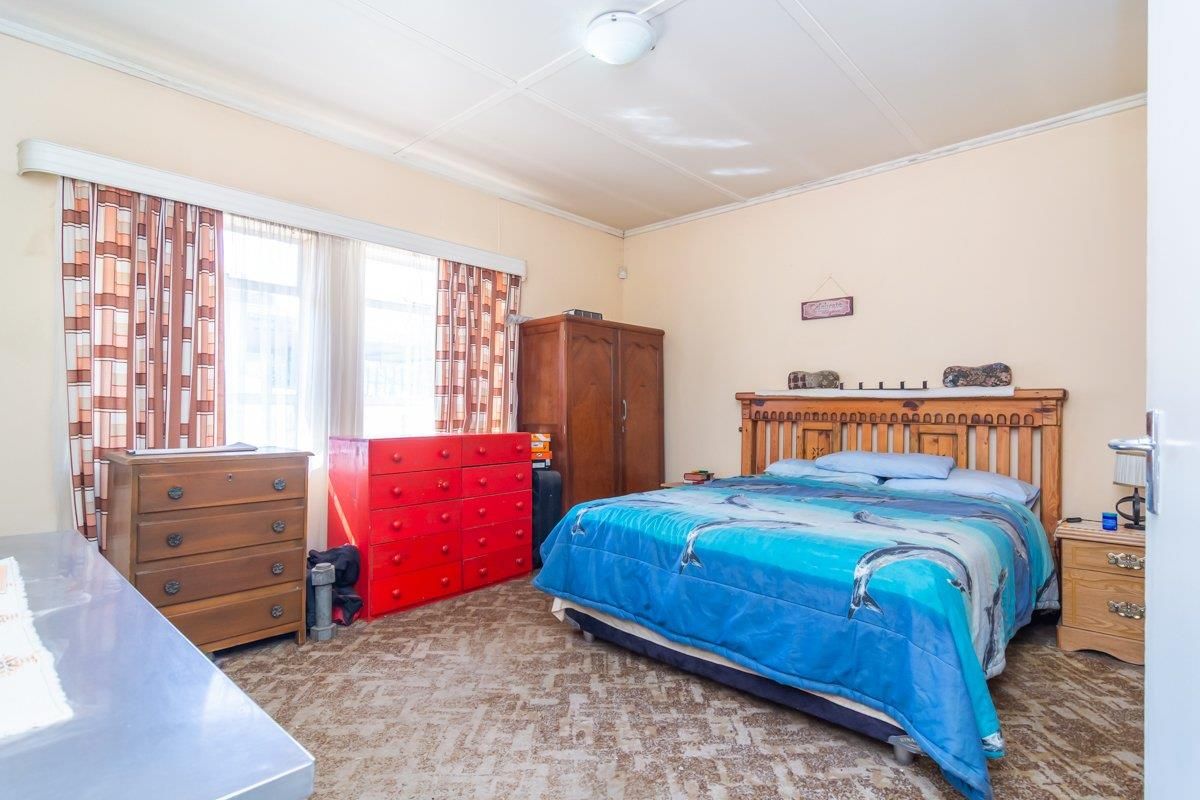 A spacious bedroom featuring large windows, neutral wall tones, and carpeted flooring, offering a functional layout ready for modernization.