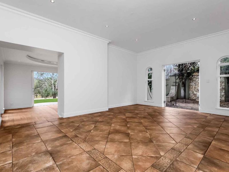 Spacious, light-filled living area featuring elegant tiled flooring, crown molding, recessed lighting, and direct access to the garden through classic french doors.