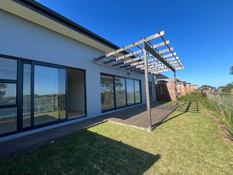 Rear exterior view featuring a timber deck with a pergola, sliding glass doors, and a landscaped garden area.