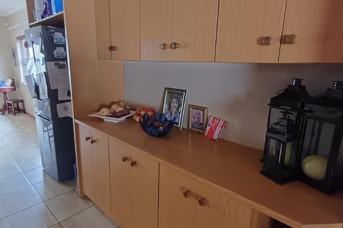 A functional kitchen area featuring light wood-toned cabinetry with ample storage and tiled flooring.
