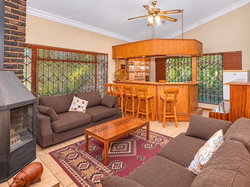 Spacious living area featuring a built-in wooden bar, a fireplace, tiled flooring, and decorative crown molding, offering a comfortable and functional entertainment space.