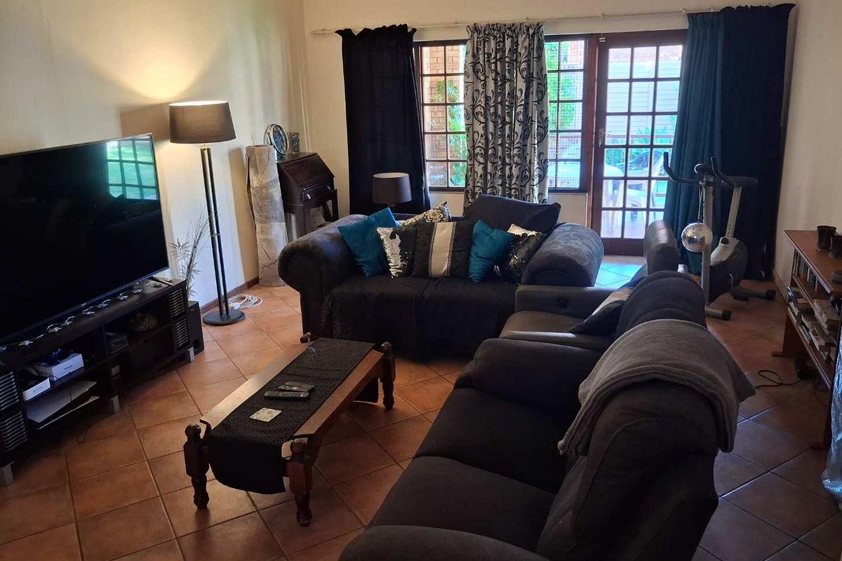 A spacious living room featuring terracotta floor tiles and direct access to the outdoor patio through glass-paned double doors.