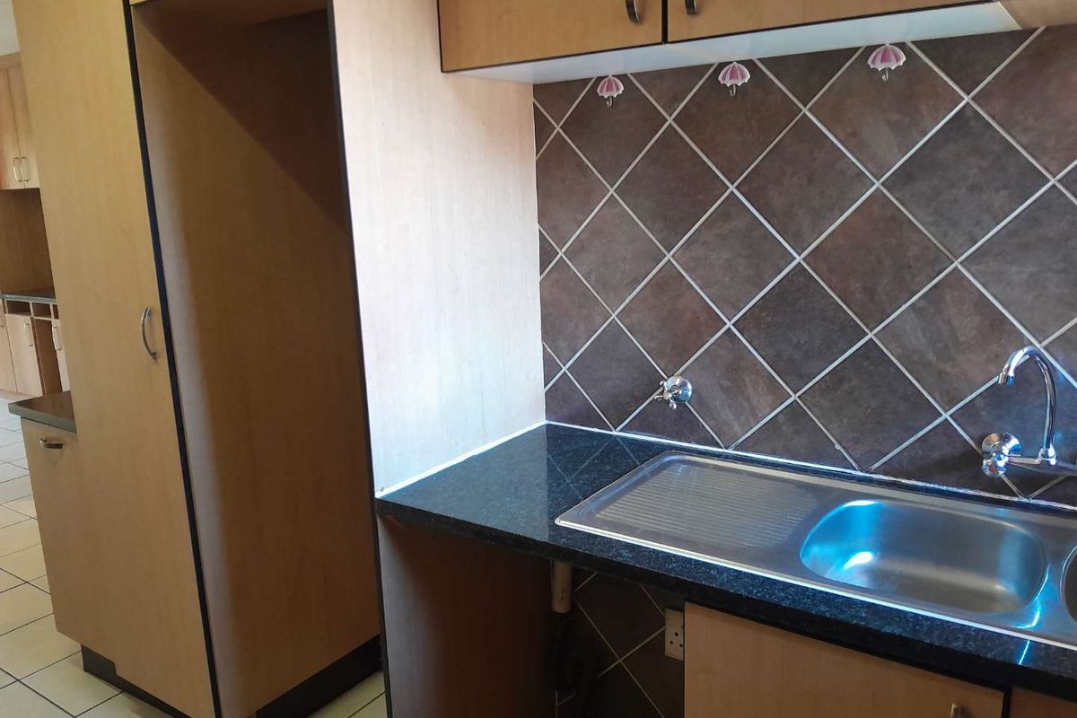 A functional kitchen area featuring laminate cabinetry, granite countertops, a stainless steel sink, and a tiled backsplash.