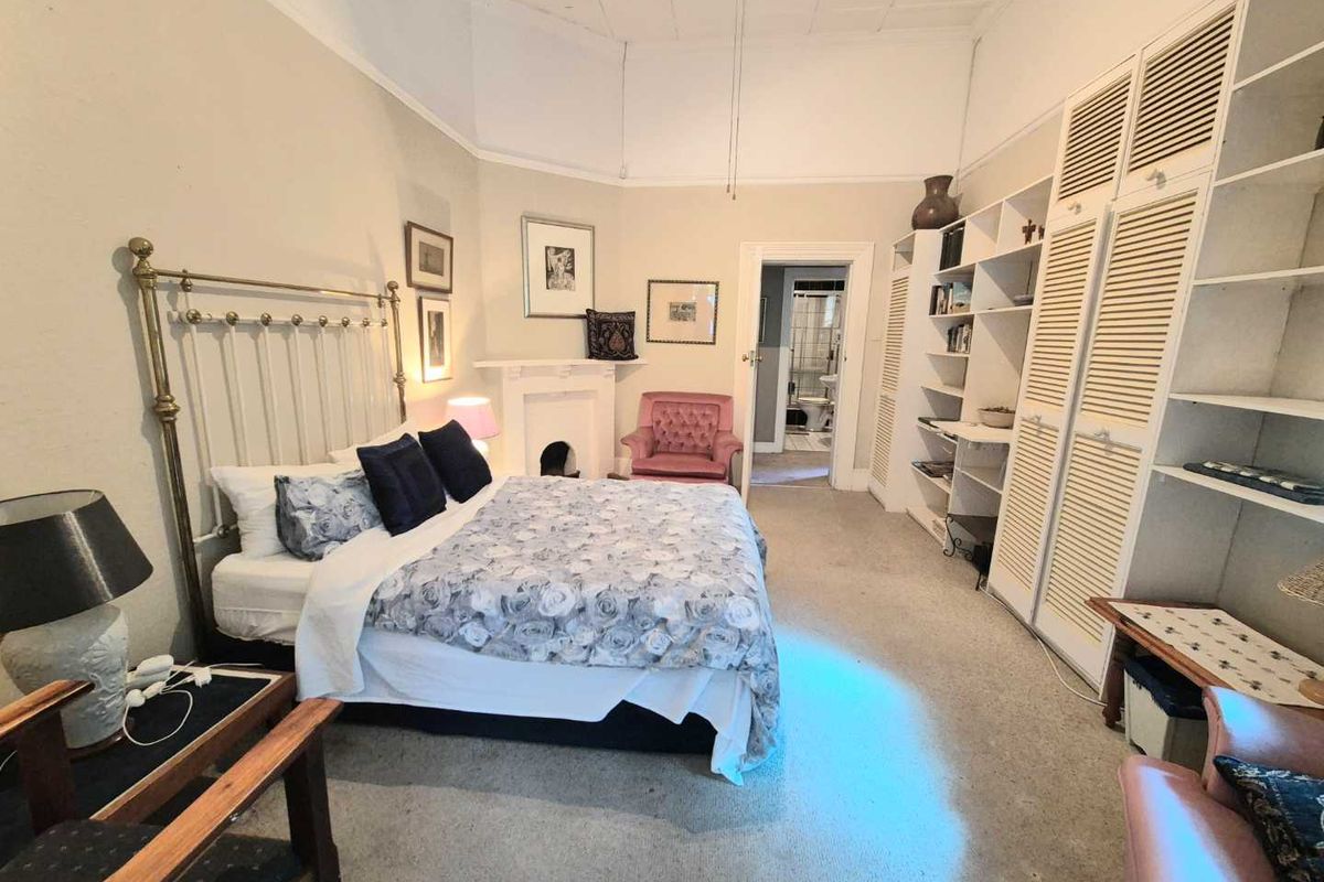 Spacious bedroom featuring built-in cabinetry, a decorative fireplace mantle, and direct access to an en-suite bathroom.