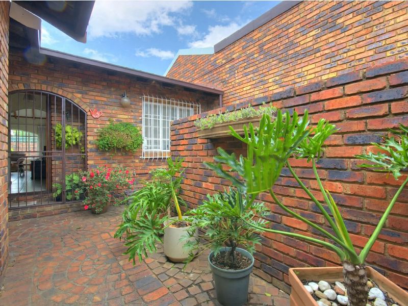 A private rear courtyard featuring facebrick walls, brick paving, and secure access points, creating a charming and enclosed outdoor living space.