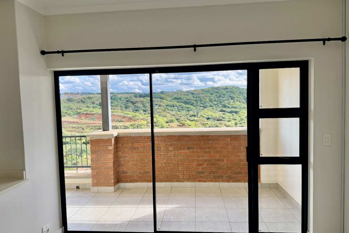 Bright living area featuring large sliding glass doors that open onto a private balcony with scenic landscape views.